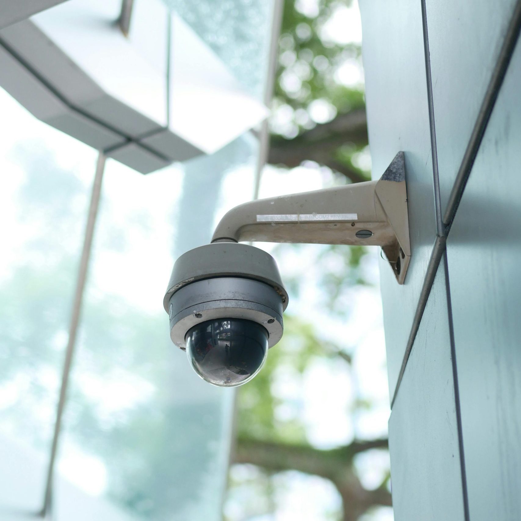 A high-tech surveillance camera installed on a modern architecture outdoor wall.